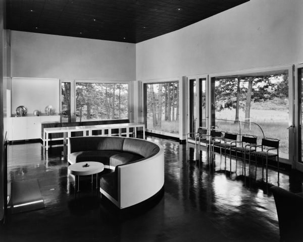 The Bertram and Irma Cahn House was designed by the architectural firm Keck and Keck as Project #213 in 1936. This photograph is taken of the living room and dining area of the Cahn house on Green Bay Road in Lake Forest, Illinois. Bertram Cahn was President and Chairman of Kuppenheimer Clothing Manufacturers in Chicago. Irma Cahn, after seeing the House of Tomorrow at the Chicago World's Fair (Century of Progress), wanted to have George Fred design her a "House of the Day After Tomorrow."