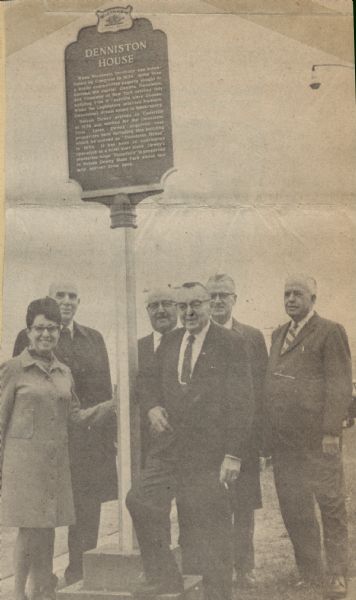 Deane and Don Oelke, front row, owners of the Denniston House Hotel, standing by the historical marker honoring the history of the Denniston House in Cassville. Behind the Oelkes stand the participants in the dedication ceremony. From left to right: Dr. L.C. Smith, who spoke on the history of Cassville, John Kujawa, president of the Grant County Historical Society, Ray Sivesind, head of the sites and markers division of the State Historical Society, and Village President R.J. Eckstein. 
