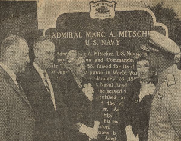 The dedication of Admiral Marc A. Mitscher, U.S. Navy historical marker in Hillsboro, the birthplace of Admiral Mitscher. Participants in the dedication and unveiling ceremony of the historical marker included, from left to right, Admiral J.J. Clark, Chairman of the Board of the Admiral Marc A. Mitscher Memorial Foundation, Wisconsin Governor Vernon Thomson, Mrs. Mitscher, widow of the admiral, Mrs. Zoe Hoevel, his sister, and Rear Admrial H.H. Caldwell, chief of the Naval air reserve training. Mrs. Mitscher and Mrs. Hoevel unveiled the marker honoring their family member to the public.  