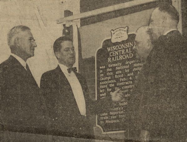 Dr. Clifford L. Lord (second from left), director of the Wisconsin State Historical Society, unveiled the Wisconsin Central Railroad historical marker at Hotel Menasha, commemorating the beginning of the railroad at the site in 1871. Other participants in the dedication ceremony included Edgar F. Zelle (left), president of the Wisconsin Central Railroad, Alderman Paul Laemmrich (second from right), president of the Menasha City Council, and George Banta, Jr. (right), a resident of Menasha. 