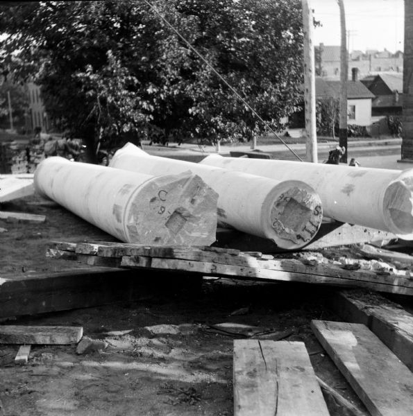 Three columns are resting on the ground on wooden supports before being installed in the facade of the Eau Claire Public Library during construction. The library opened in 1904.