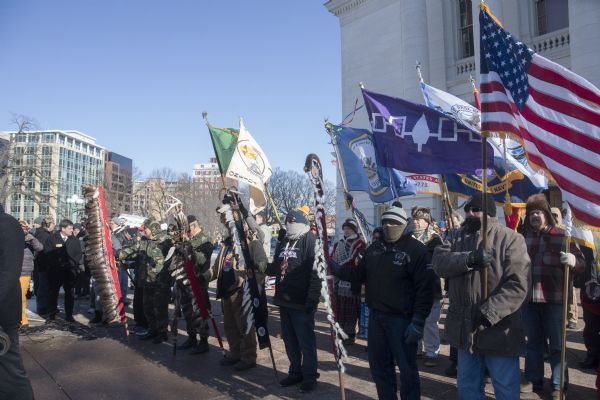 Save the Mounds demonstration at the Capitol Square against Assembly Bill 620. Flag and Standard bearers are lined up behind the speakers. In the background on the right is the Wisconsin State Capitol.