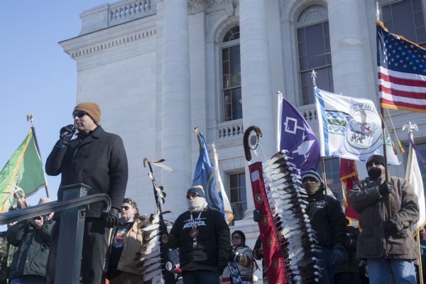 Save the Mounds demonstration around the Capitol Square against Assembly Bill 620. View looking up at the Flag and Standard bearers lined up behind the speaker, Henning Garvin of the Ho Chunk Nation. In the background is the Wisconsin State Capitol.