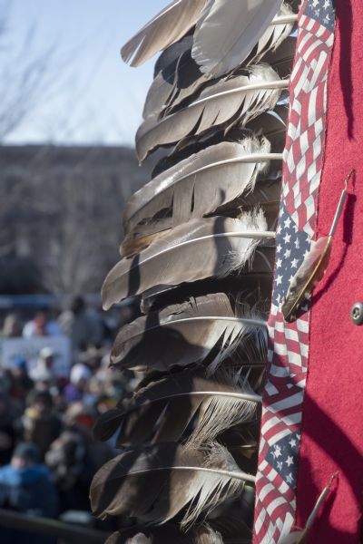 Save the Mounds demonstration around the Capitol Square against Assembly Bill 620. There is a feathered eagle staff in the foreground of the image. In the background, out of focus, is the crowd attending the demonstration.