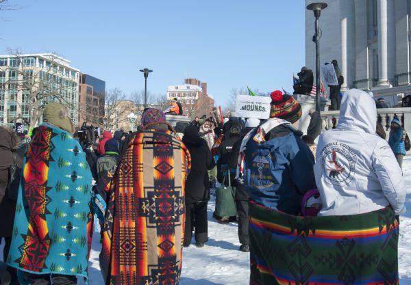 Save the Mounds demonstration around the Capitol building against Assembly Bill 620. Three blankets displaying Native American designs are being used to keep warm.