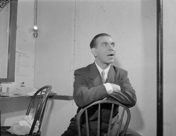 Eddie Cantor sitting in a chair backwards.