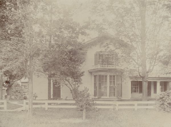 The Enoch B. Fargo residence shows a two-story Greek revival house with a gable wing with bay window facing the road. There is a full height ell on the left and a one-story ell with a columned porch on the right. There is a short balustrade above the bay window; all the windows have shutters. There is a hitching post in front of a fence which encloses the yard. Enoch B. Fargo, along with several of his brothers, was one of the earliest settlers in Lake Mills, arriving in 1844. He was involved in various business ventures there.