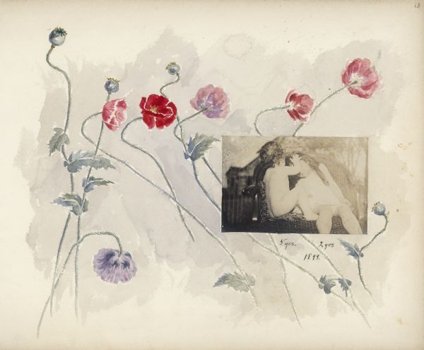 Hand-painted poppies adorn an album page which features a photograph of Stuart, left, and Dorothy Fargo. In the photograph, Stuart is naked and has placed his hand on the forehead of his older sister. They are seated on an upholstered settee. There is a building and trees in the background suggesting that the photograph was taken outdoors.   