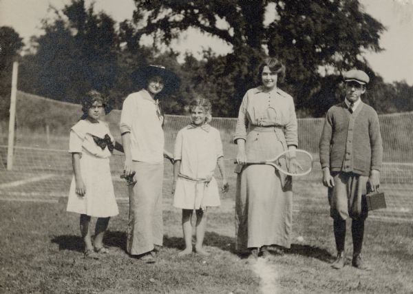 Dorothy Fargo, holding racquet, and her brother Stuart, are posing with an unidentified woman and two girls in front of a tennis net. The handwritten caption reads: "Playing Tennis with McDonalds."
