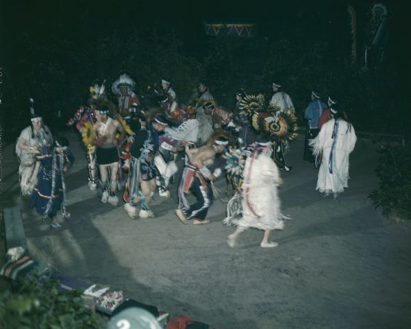 A group of men and women, dressed in ceremonial clothing, performing the Snake Dance at the Stand Rock Indian Ceremonial.