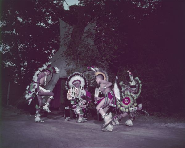 Three men and a young boy (Little Bobby Bird) are dancing as a man is playing a drum.