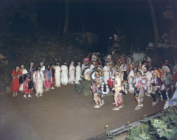 Elevated view of a group of men and women are lined up in a row, performing the Snake Dance at the Stand Rock Indian Ceremonial.