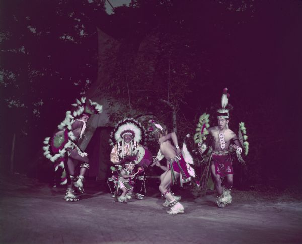 Three men and a young boy (Little Bobby Bird) are dancing as a drummer is playing.