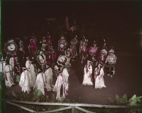 Elevated view of a group of men and women walking in line of pairs as they perform the Green Corn Dance at the Stand Rock Indian Ceremony.