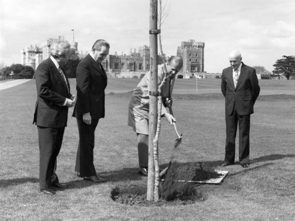 University of Wisconsin professor of plant pathology and forestry Eugene B. Smalley (1926-2002), right, is watching as Prince Philip, Duke of Edinburgh, is shoveling dirt around a newly planted hybrid elm from Wisconsin on the grounds of Windsor Castle. The two men at left are unidentified. Smalley devoted his career to developing elm trees that were resistant to Dutch elm disease. His trees have been planted worldwide to replace elms lost to the disease.