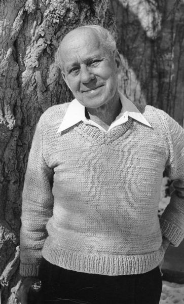 Walter Scott (1911-1983) posing in front of the gnarled trunk of a box elder tree at his home, Hickory Hill House. Scott was employed by the Wisconsin Department of Conservation, and later by the Department of Natural Resources, for many years. From 1946 until his retirement in 1974, he maintained the records of the "big tree program" which listed the largest trees in the state.