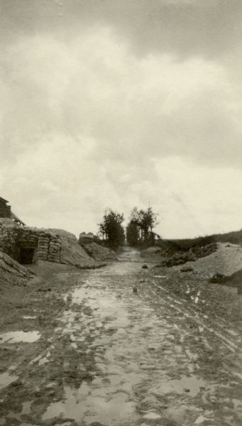 View down center of road towards bunkers and trees. Captioned: "Route 44, a national road, hundreds of years old. It is too close to the Boche to be used in the day. Notice that it is lined by trees in the background."