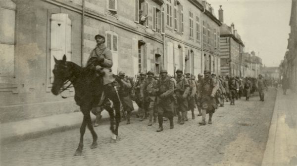 The band and infantry marching together as they leave Ste. Menehould. Captioned: "Infantry following the band on their march 'out.' Ste. Menehould."