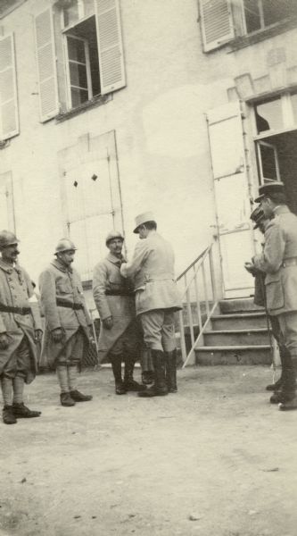Three soldiers standing in front of a building while being decorated. Captioned: "Three French stretcher-bearers being decorated for bravery. Vaux Varennes."