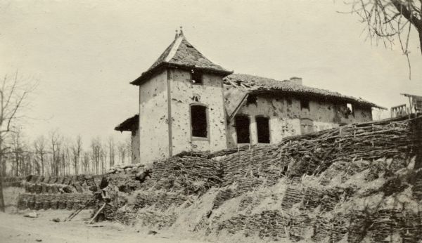 Damaged roof and walls of a french bakery on a hill. Captioned: "'Le Four de Paris' (Oven of Paris), the quaint old bakery, after which this part of the Argonne sector received its name. April, 1915, saw heavy fighting here."