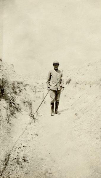 View of a man standing in a trench. Captioned: "A. Rodriguez, Corporal of "brancardier," taken in a Russian trench in the Champagne, near Auberive. Notice the poor protection the trenches offer. The Foreign Legion did great work in taking Mont Cornillet to the left of this place." 