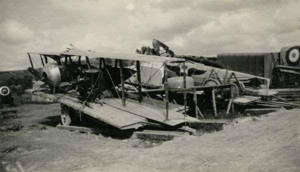 Damaged airplanes sitting on wooden planks. Captioned: "A Nieuport 'sent up' for repairs."