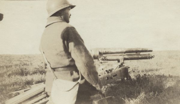 Soldier standing in a field next to a machine gun. Caption reads: "A 37 m.m. gun used largely against Machine gun implacements. It is accurate and quick firing."
