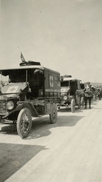 A line of ambulances from the S.S.U 12 convoy getting ready to leave Recy. Caption reads: "The ambulances of S.S.U 12 lined up outside of Recy waiting for the convoy to start. Tom O' Connor in the background."