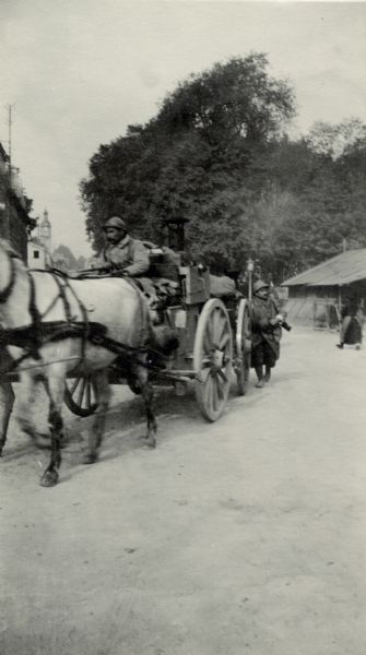 Two men transporting military utilities or equipment with a horse-drawn vehicle.