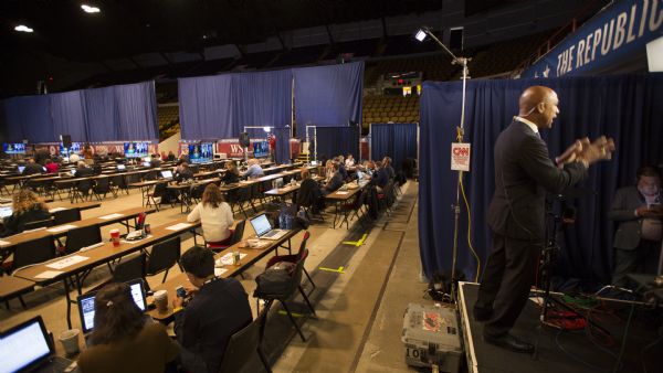 Reporters and television crews setting up their equipment in a large auditorium outside the Republican presidential debate. On the right a reporter for CNN is standing on a stage.