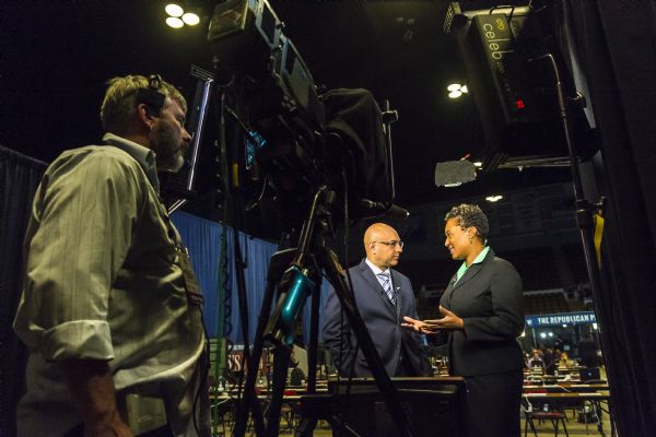Ali Velshi interviewing Wisconsin State Senator (4th District) Lena Taylor as a camera operator is filming them. They are standing in the press staging area within the Panther Arena during the Republican presidential debates.