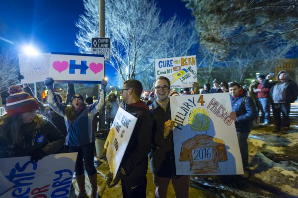 People holding up signs supporting Hillary Clinton amongst a group of anti-Hillary demonstrators posing with their signs.
