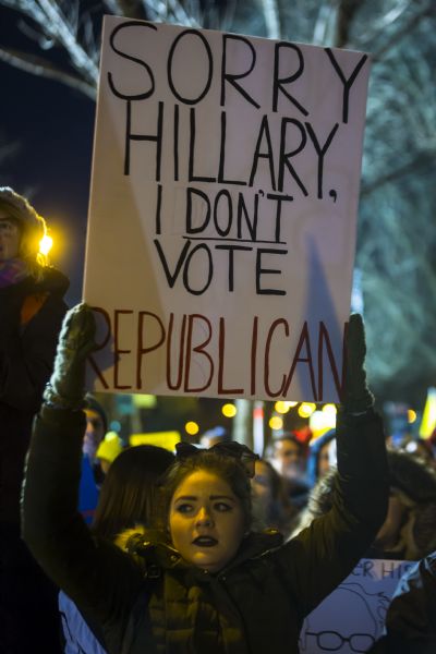 A young woman is standing in a crowd of people and holding up a sign reading: "Sorry Hillary, I Don't Vote Republican."