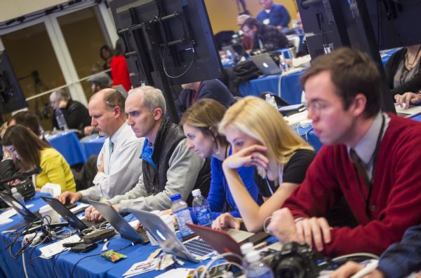 A row of journalists are sitting at a long table in the spin room as they work on their computers or watch the debate. Among them is Scott Bauer on the far left, the political correspondent for the Associated Press.