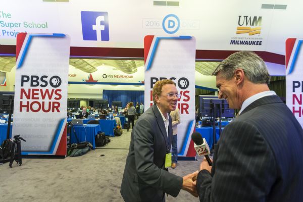 Journalist and author John Nichols, left, shaking hands with Greg Jeschke, a television journalist for WKOW, after being interviewed in the spin room at the Democratic presidential debate.