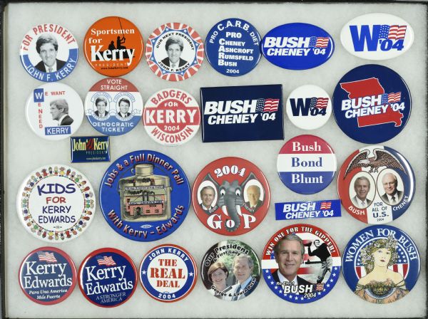 Framed assortment of campaign buttons for John Kerry and running mate John Edwards, and George W. Bush and running mate Dick Cheney. One button shows a ring of cartoon children holding hands and reads: "Kids For Kerry, Edwards." Another references the then popular Atkins diet reading: "Pro C.A.R.B diet, Pro Cheney, Ashcroft, Rumsfeld, Bush."