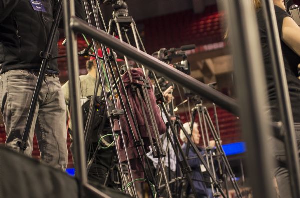 Members of the press setting up while standing behind their cameras and tripods at the Bernie Sanders rally being held in the Kohl Center.