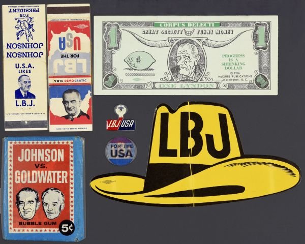 Seven items in an assortment of political campaign ephemera for Lyndon B. Johnson. Includes an anti-Johnson funny money dollar bill with hand-drawn images such as a lemon, a portrait of Lyndon B. Johnson, and bull horns. There are two matchbooks: one with a white background with blue text that reads: "U.S.A. likes L.B.J" and Johnson for President" with a donkey playing a bass drum; and "LBJ for USA." There is one Bazooka bubble gum wrapper that reads: "Johnson vs. Goldwater;" one yellow cowboy hat sticker that reads: "LBJ;" one lenticular sticker that displays a blue background with red outlined, white text that reads: "LBJ" and red, white, and blue stripes with black text that reads: "For the USA." There is also a metal fold over rectangular shirt pin with a red and blue background with white text that reads: "LBJ, USA."