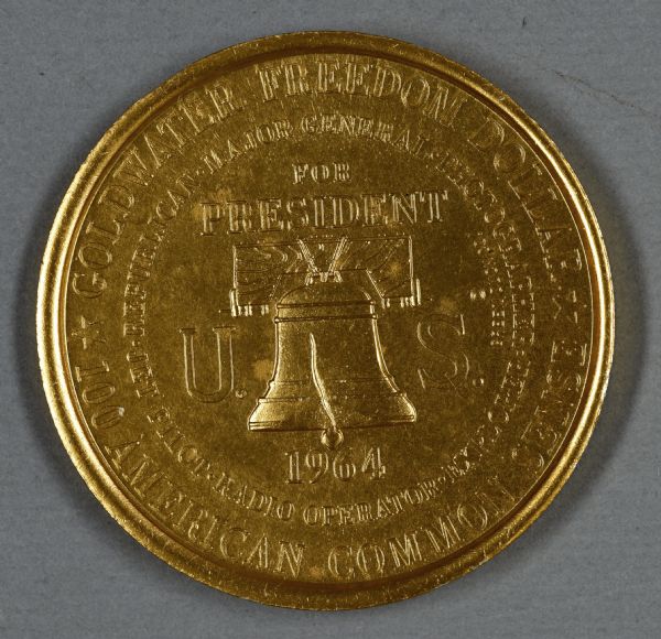 Coin with an image of the Liberty Bell, surrounded by the words: "Goldwater Freedom Dollar, 100 American Common Sense, Major General, Photographer, Republican, Jet Pilot, Radio Operator, Explorer, For President, U.S. 1964."