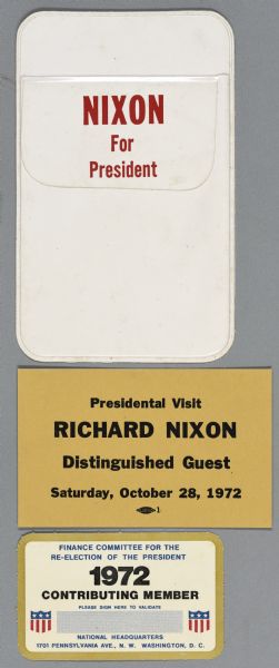 Three items in an assortment of political campaign ephemera for Richard Nixon. At the top is a white pocket pen protector with red text that reads: "Nixon for President." In the center is a yellow card with black text that reads: "Presidential Visit Richard Nixon Distinguished Guest, Saturday, October 28, 1972." At the bottom is a card that reads, in part: "1972 Contributing Member."