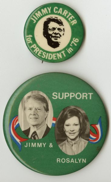 Two presidential political campaign buttons for Jimmy Carter. The button on top has a green circular border around a black and white portrait of Jimmy Carter and reads: "Jimmy Carter for President in '76" within the border. The bottom button is also green, and includes a red, white, and blue ribbon behind two oval black and white portraits of Jimmy and Rosalyn Carter, and reads: "Support Jimmy & Rosalyn."