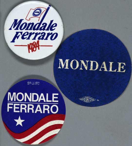 Two presidential political campaign stickers and one button for Walter Mondale and Geraldine Ferraro. One sticker is blue with white text and reads: "Mondale," while the other sticker has red and white wavy stripes with one white star against a blue background and reads: "Mondale Ferraro." The political button is white with blue and red  text and reads: "Mondale Ferraro 1984." The ascender of the "d" in Mondale is elongated to look like a flag pole for the red outline of a flag which reads: "UAW."