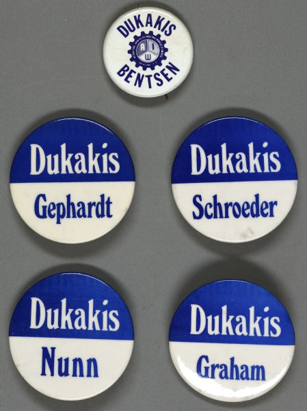 Five presidential political campaign buttons for Michael Dukakis. The button at the top is white with blue text that reads: "Dukakis Bentsen," and includes a sprocket wheel displayed in the middle with the letters "AIW" for International Union Allied Industrial Workers of America. The other four buttons are of the same design, with text at the top, that reads: "Dukakis" in white on a blue background, with a different name at the bottom on each button, in blue text on a white background, for: "Gephardt; Schroeder; Nunn; Graham." 