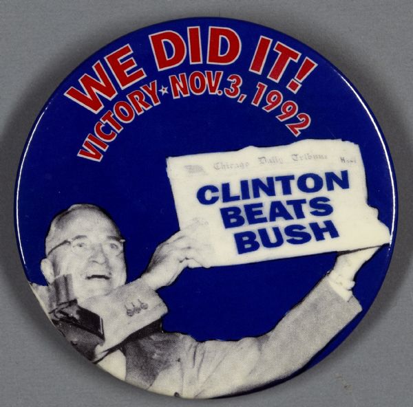One presidential political campaign button for Bill Clinton. It has a blue background with a black and white portrait of President Harry S. Truman holding up Chicago Daily Tribune newspaper with a superimposed headline that reads: "Clinton Beats Bush." At the top of the button, red text reads: "We did it! Victory Nov. 3, 1992."