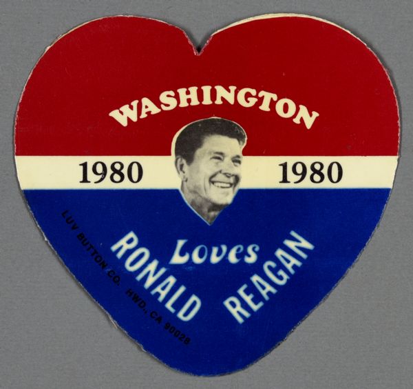 Presidential political campaign ephemera for Ronald Reagan. This handcut heart-shaped political sign is red, white, and blue with a black and white headshot of Ronald Reagan. It reads: "Washington Loves Ronald Reagan 1980."
