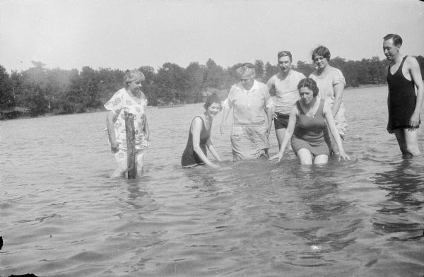 Two men and five women posing in knee-high water. Leonore Judkins Middleton is crouching in front of her husband, Forest Middleton. The woman to the left of Forest may be Leonore's mother, Cora Judkins.   