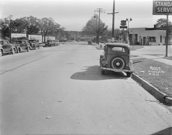 Looking east on University Avenue from the intersection with Grand Avenue, with the rear view of an automobile in the foreground. On the right is Samuel Fiore's Phillips 66 service station, 2549 University Avenue. This was the site of a motorcycle and truck accident.
