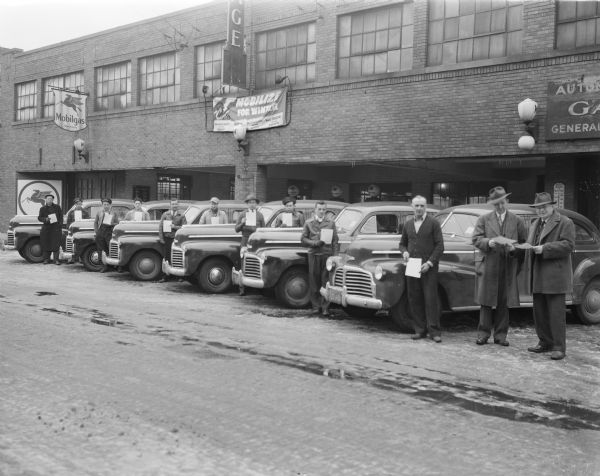 Six Chevrolet automobiles (possibly taxis) and 10 drivers holding pledge cards outside the side entrance to Friede Storage Garage (previously known as Purcell's Auto Co.), 434 W. Gilman Street.