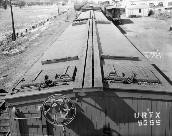 Elevated view of the top of an Oscar Mayer refrigerated railroad car, Chicago & Northwestern #URTX 5365 with a view of the Oscar Mayer rail yards. There is a Trachte building in the background.