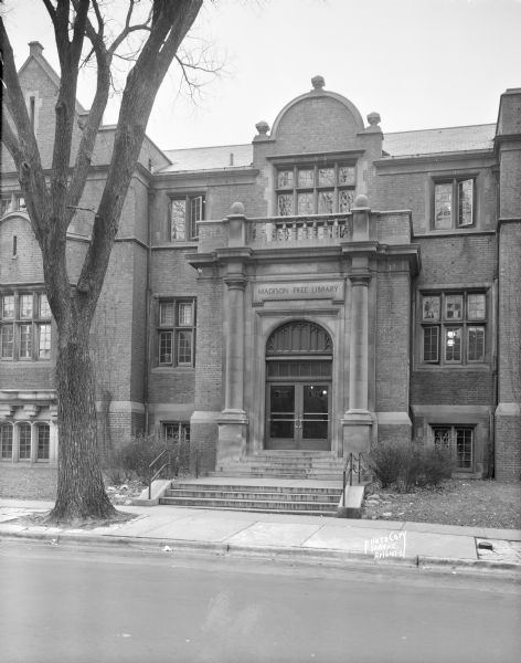 View across street towards the entrance to the Madison Free Library, 206 North Carroll Street. The library was built with Carnegie money and opened in 1906. The name changed to Madison Public Library in January of 1959. This building was torn down in 1965 when the library moved to a new building at 201 West Mifflin Street.